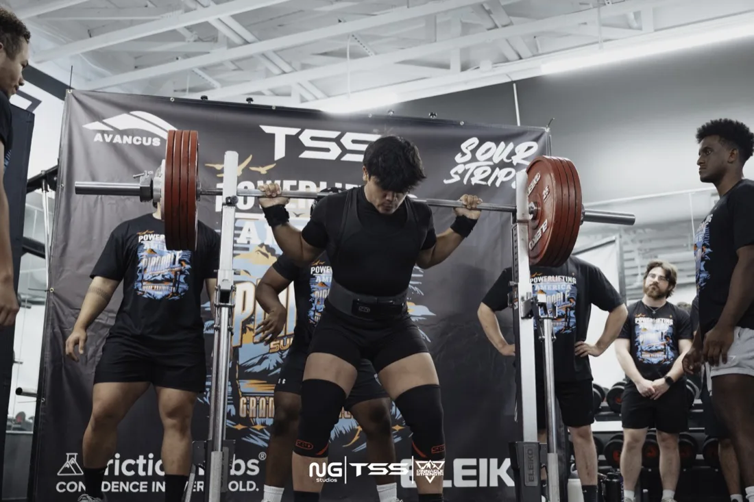 Athlete performing a squat at a powerlifting competition, photographed by NG Studios