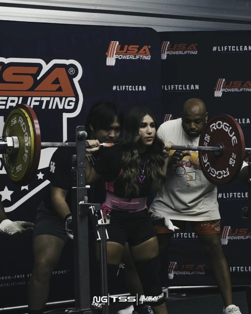 Powerlifter with spotters preparing a squat, photographed by NG Studios
